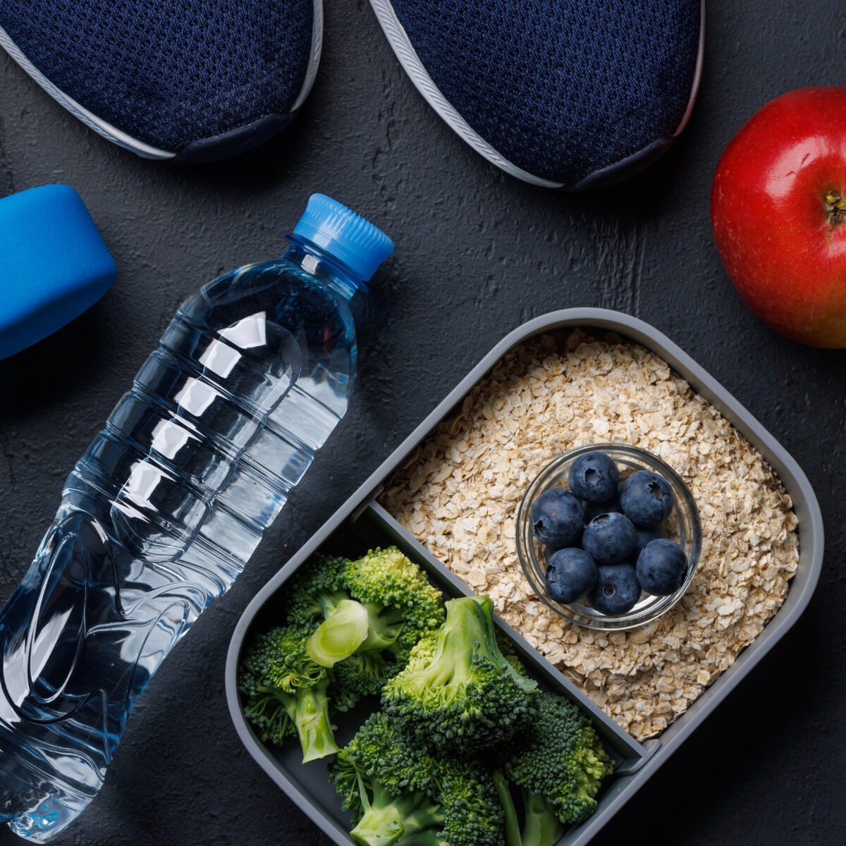 Nourriture saine dans un bento, bouteille d'eau, pommes, chaussure et poids