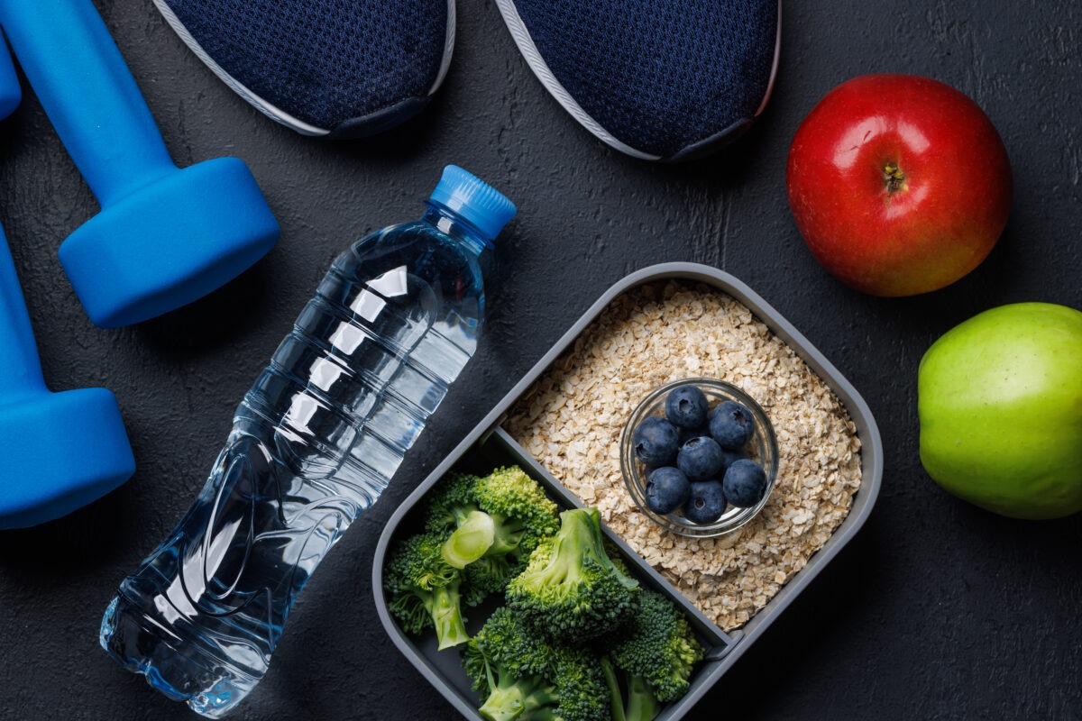 Nourriture saine dans un bento, bouteille d'eau, pommes, chaussure et poids