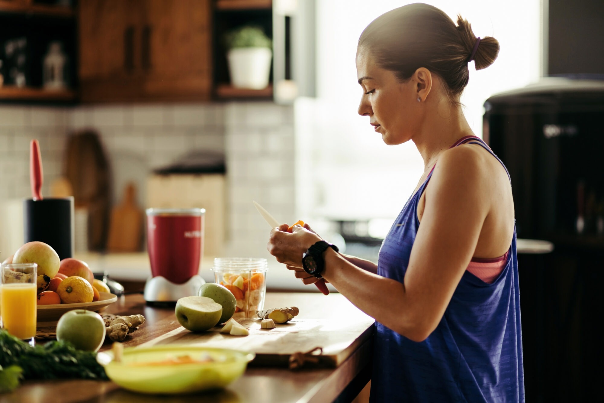 Femme en tenue de sport préparant son petit déjeuner dans la cuisine